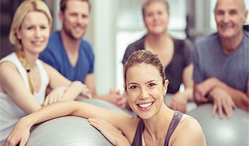 Group of people using exercise balls as chairs in a workout session.